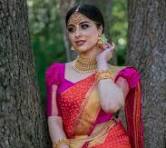 The ensemble featured in the image is a traditional Kanchipuram Silk Sari (also known as a Kanjivaram pattu sari) paired with a contemporary magenta puff-sleeve blouse.